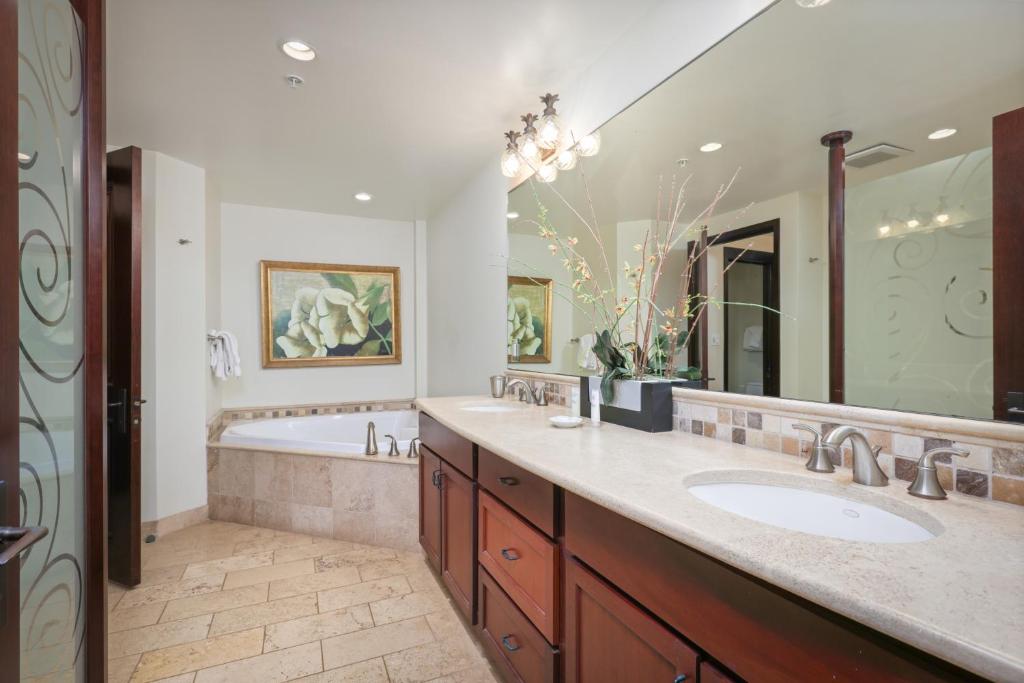 a bathroom with two sinks and a tub and a large mirror at Waipouli Beach Resort and Spa Kauai by OUTRIGGER in Kapaa