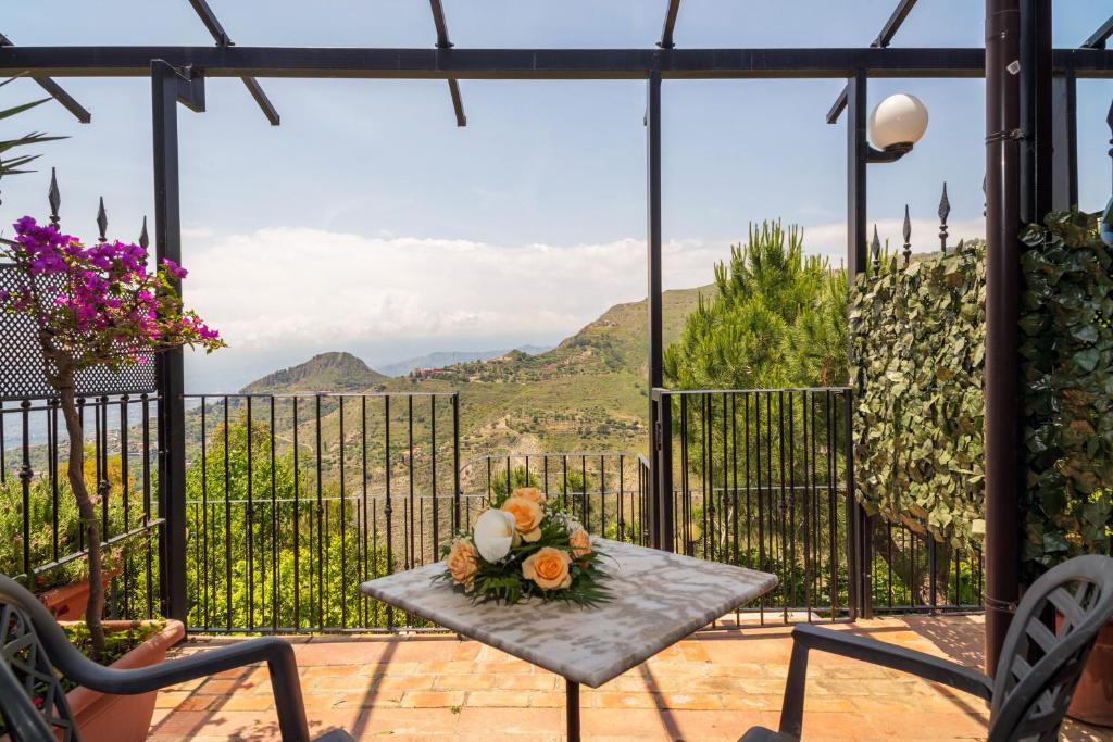 einen Tisch mit einem Blumenstrauß auf einer Terrasse in der Unterkunft Garden Cottage I Dammusi - Limoni in Castelmola