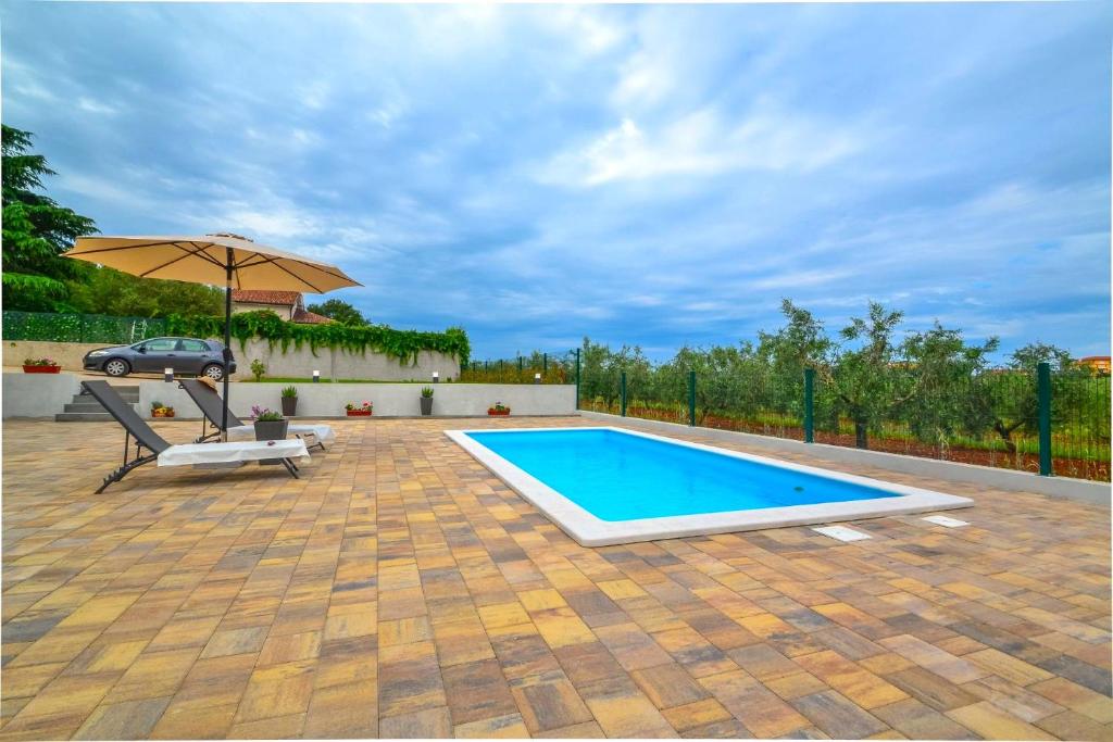 a swimming pool with a chair and an umbrella at Apartment Kaplja in Novigrad Istria