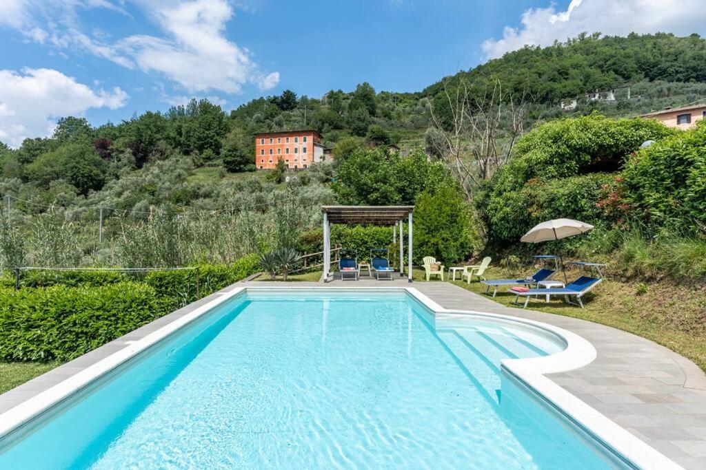 una piscina con una casa en el fondo en * Villa Ulivi - Private Pool with Panoramic Views, en Barga