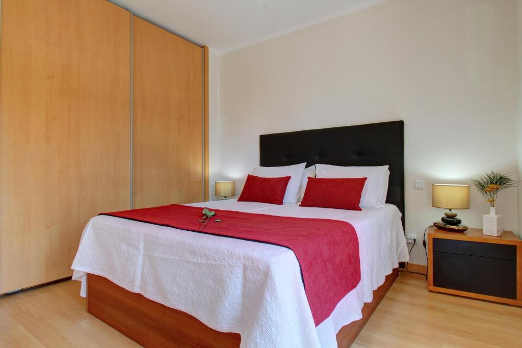 a bedroom with a large bed with red pillows at Rooftop pool, 200m from sea, city center in Olhão
