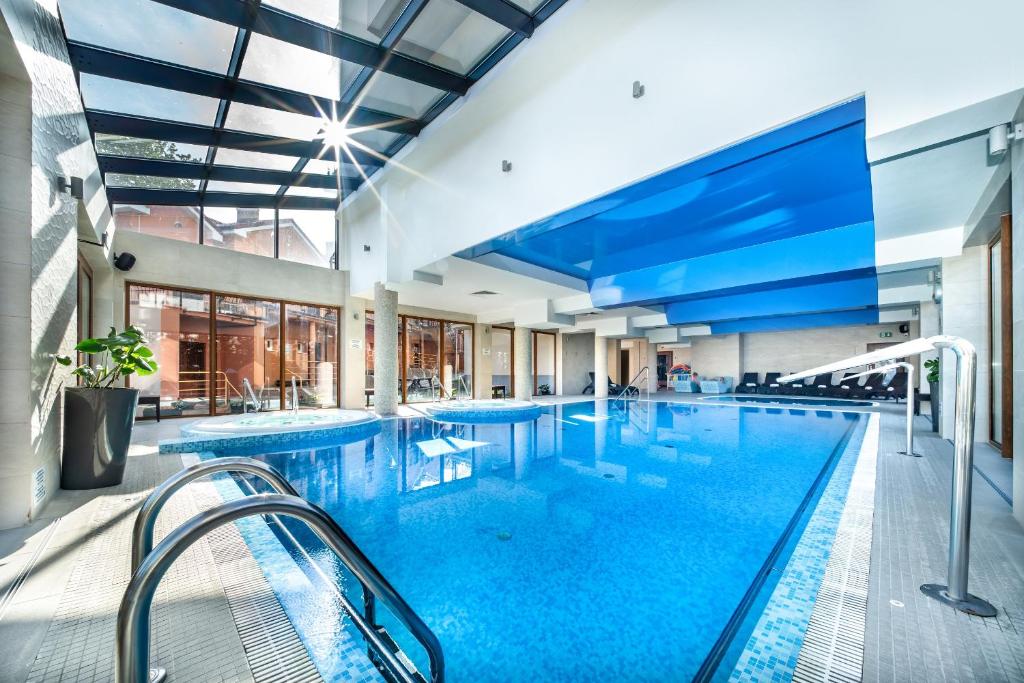 a large swimming pool with a large tv in a building at Sunset Spa in Rewal