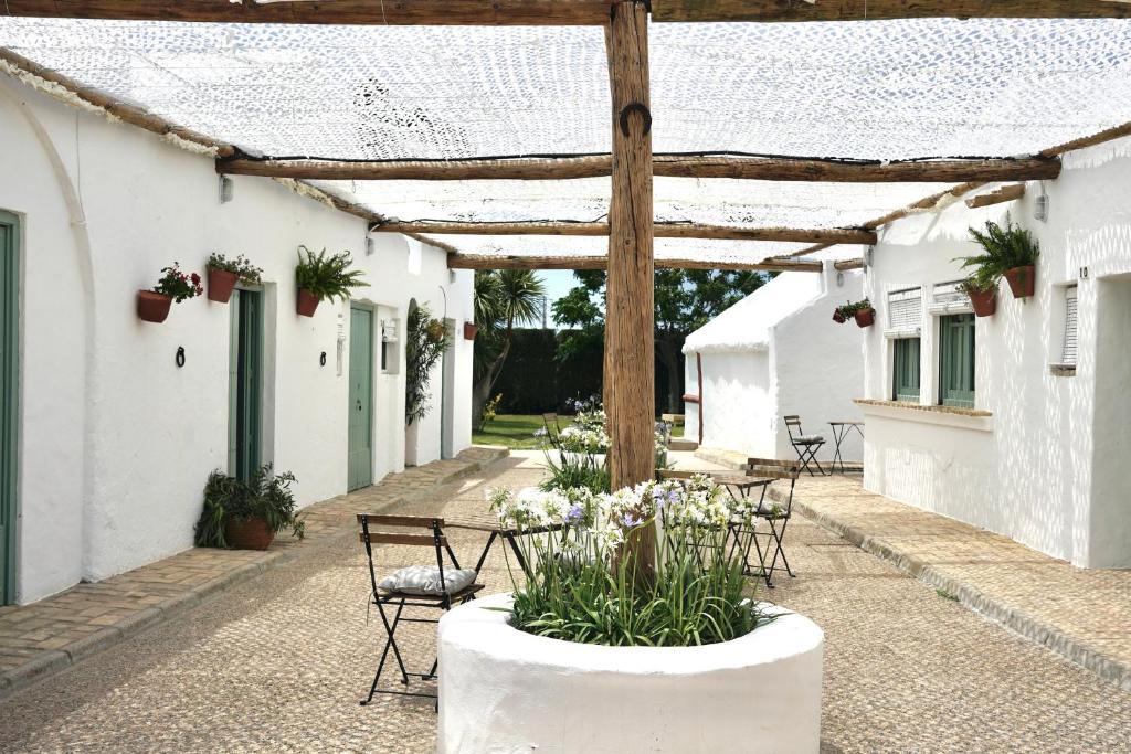 un patio con mesas, sillas y una pérgola en Alojamiento rural CASAPIÑA, en Conil de la Frontera