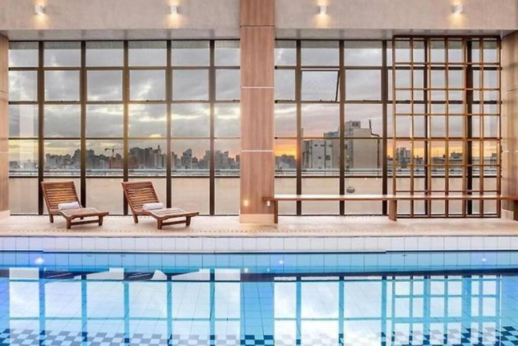 a swimming pool with two chairs next to a building at Flat Avenida Independência in Porto Alegre