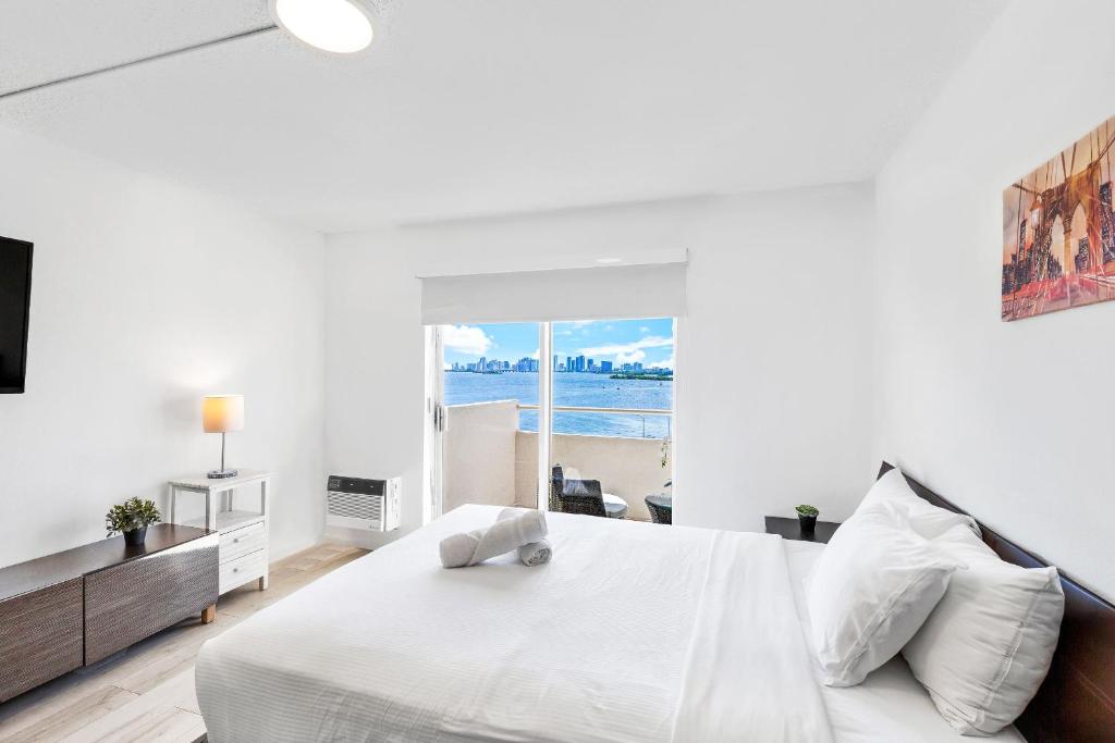 a white bedroom with a bed and a view of the ocean at Breath-taking views from this cozy studio in Miami Beach