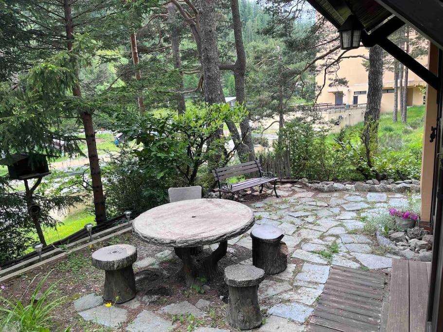 une table et des tabourets dans un jardin avec un banc dans l'établissement 2 pièces jardin au pied des pistes, à Valdeblore