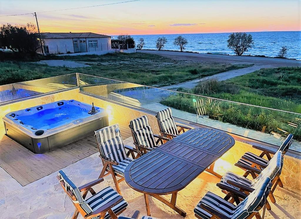 a patio with a table and chairs and a hot tub at Villa Arkadia Seafront Villa Ai-Lagoudis Beach in Kyparissia