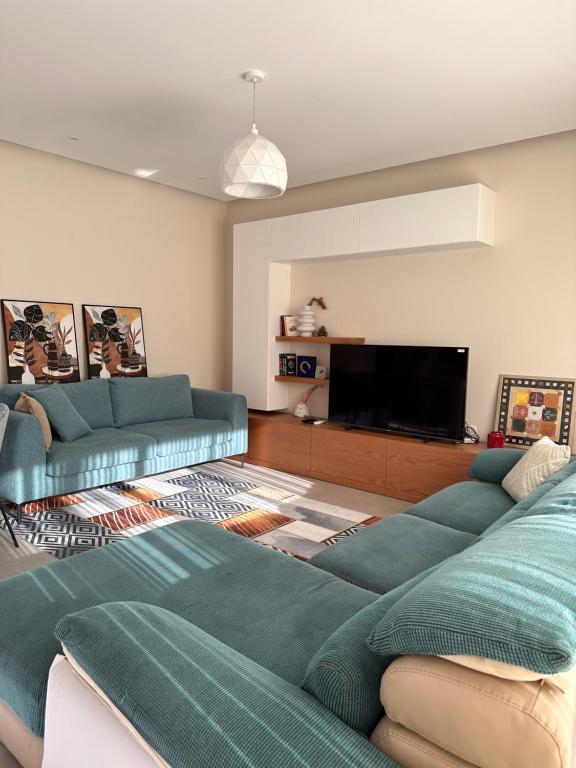 ein Wohnzimmer mit blauen Sofas und einem Flachbild-TV in der Unterkunft ByBreeze Appartments in Durrës