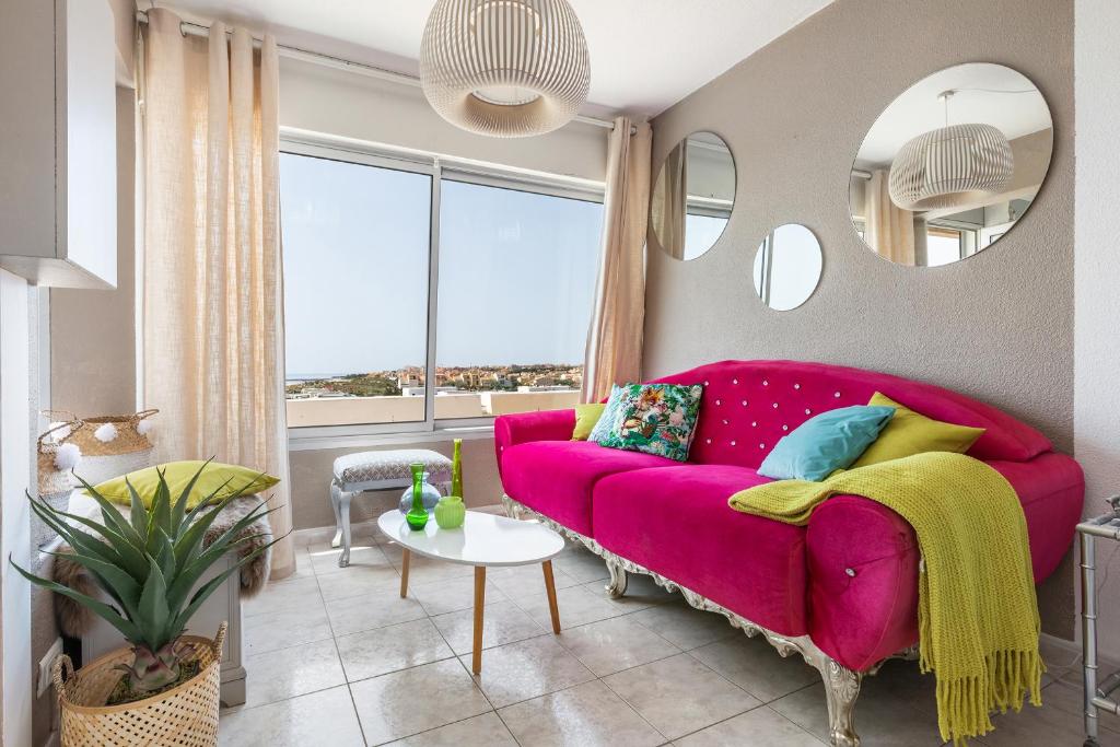 - un canapé rose dans le salon doté d'une fenêtre dans l'établissement Happy coral Port nature, au Cap d'Agde