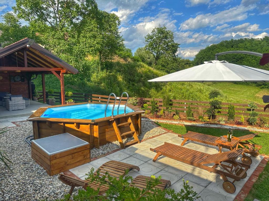 einen Pool mit einem Tisch, Bänken und einem Sonnenschirm in der Unterkunft Kuća za odmor Zora 