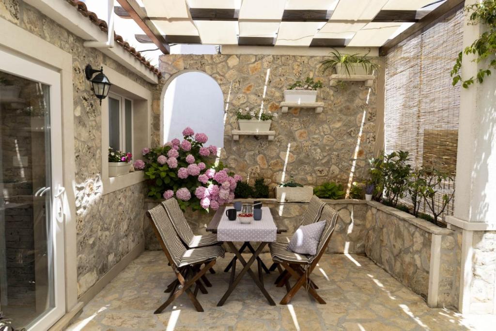 un patio con tavolo, sedie e fiori di M&T a Supetar (San Pietro di Brazza)