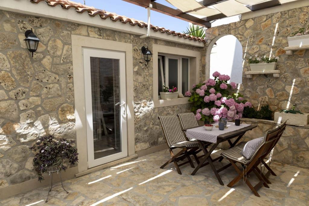 un patio con tavolo e sedie su un muro di pietra di M&T a Supetar (San Pietro di Brazza)
