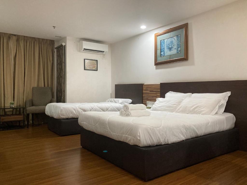a hotel room with two beds and a chair at Monolocale Stay (Studio Apartment KBCP) in Kota Bharu