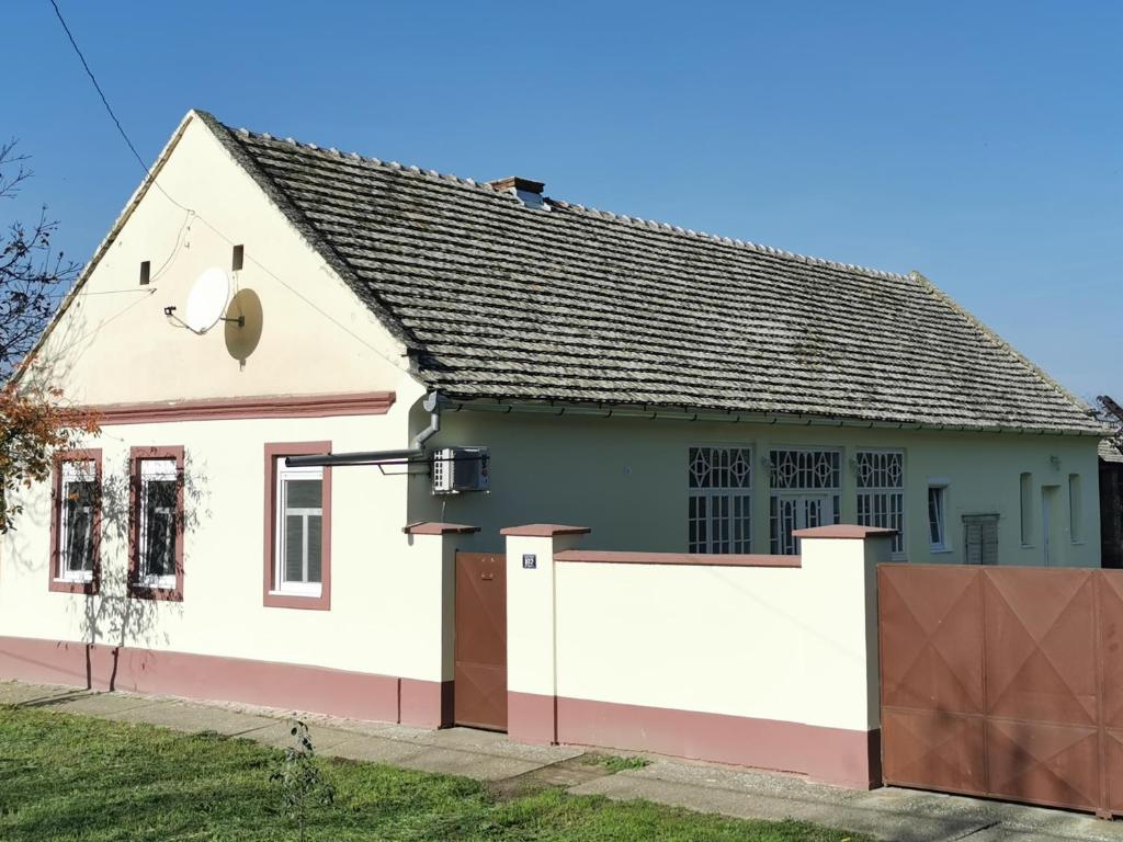 a white house with a gate and a fence at Kod Bake in Novi Bečej