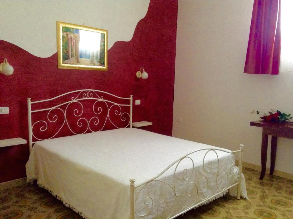 モルチャーノ・ディ・レウカにあるB&B Lindaの赤い壁のベッドルーム1室(白いベッド1台付)