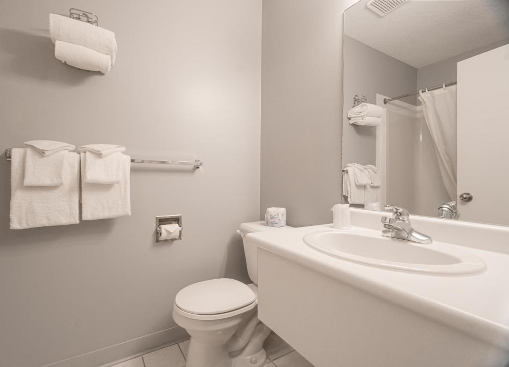 a white bathroom with a toilet and a sink at Mountain View Inn in Canmore