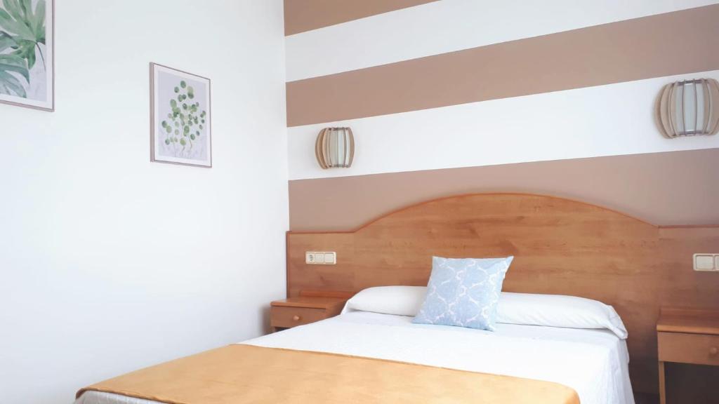 Schlafzimmer mit einem Bett mit einem Kopfteil aus Holz in der Unterkunft Habitaciones Ninfa in Villalonga