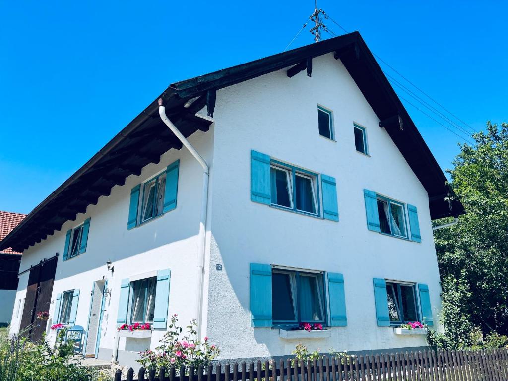 a white house with blue windows and a fence at Charming historical farmhouse in Finning