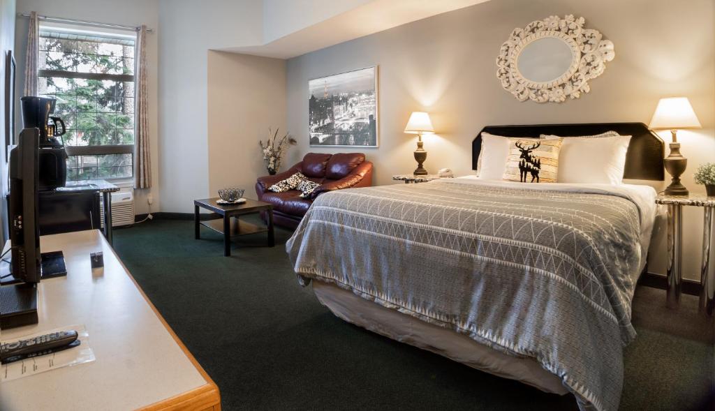 a bedroom with a bed and a couch and a television at Mountain View Inn in Canmore