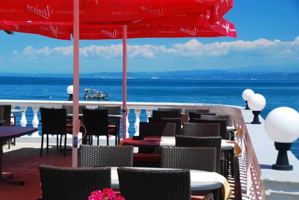 a patio with tables and chairs with the ocean in the background at Hotel Fiesa in Piran