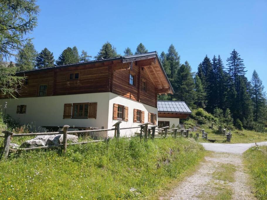 uma casa num campo com uma estrada de terra em Chalet Neuhofalm Obertauern mit Sauna und Hobbyraum em Obertauern