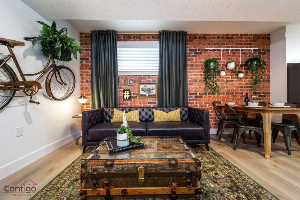 uma sala de estar com um sofá e uma parede de tijolos em Luxe New York Style Bsmt Suite, Near DT & WEM, King Bed, WiFi em Edmonton
