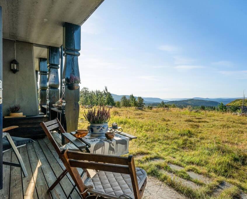 einen Tisch und Stühle auf einer Veranda mit Blick auf ein Feld in der Unterkunft Leilighet sentralt på Beitostølen in Beitostøl