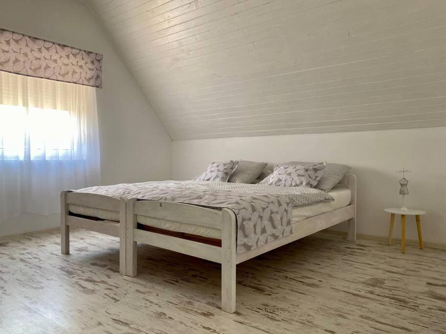 uma cama num quarto branco com uma janela em Zsuzsi Vendégház Visz em Visz