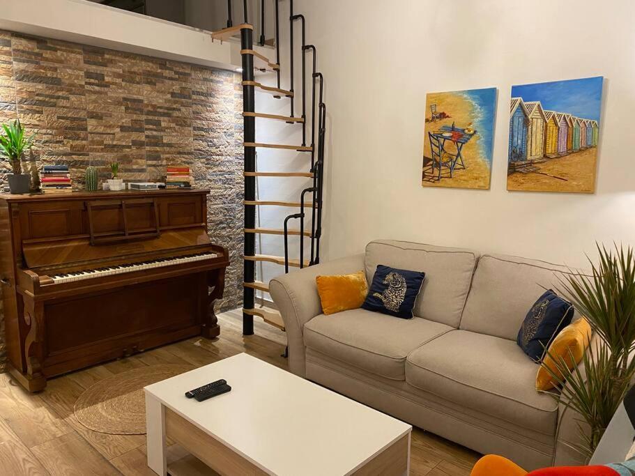 a living room with a couch and a piano at Charmante maison avec extérieur à deux pas des remparts in Aigues-Mortes