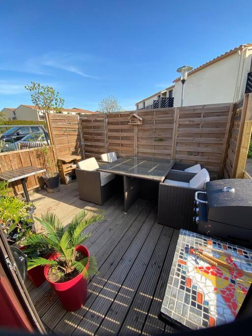 a patio with a table and plants on a deck at Charmante maison avec extérieur à deux pas des remparts in Aigues-Mortes