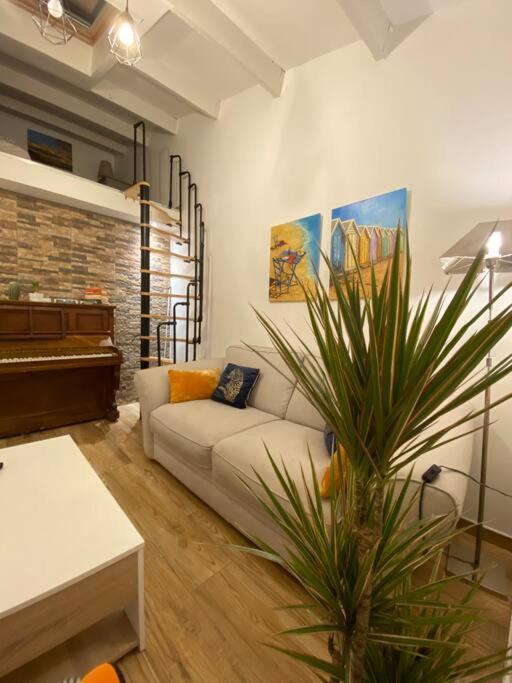 a living room with a white couch and a piano at Charmante maison avec extérieur à deux pas des remparts in Aigues-Mortes