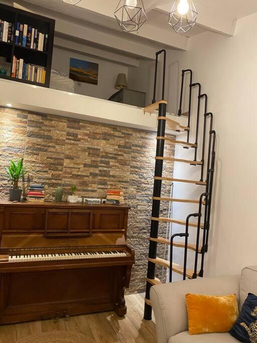 a room with a piano and a spiral staircase at Charmante maison avec extérieur à deux pas des remparts in Aigues-Mortes