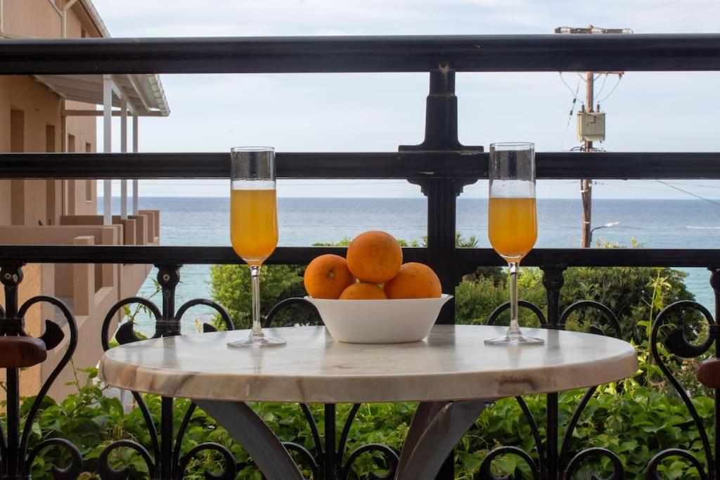 a table with a bowl of oranges and two glasses of orange juice at Vaso Alykanas Studios in Alikanas