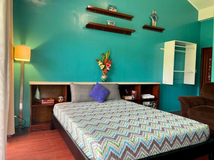 a bedroom with a bed with a blue wall at Ngermid Oasis-Spacious Studio Loft W/ Garden Views in Koror