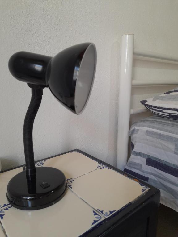 a black lamp sitting on a table next to a bed at Rose Rooms in Faro