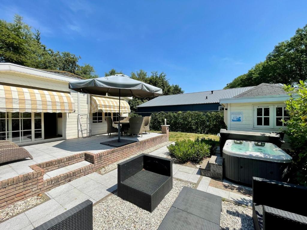 a patio with an umbrella and a swimming pool at Modern Holiday Home in Kaatsheuvel with bubble bath in Kaatsheuvel