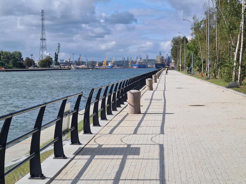 uma fila de bancos ao lado de uma massa de água em Lux New Port em Gdańsk
