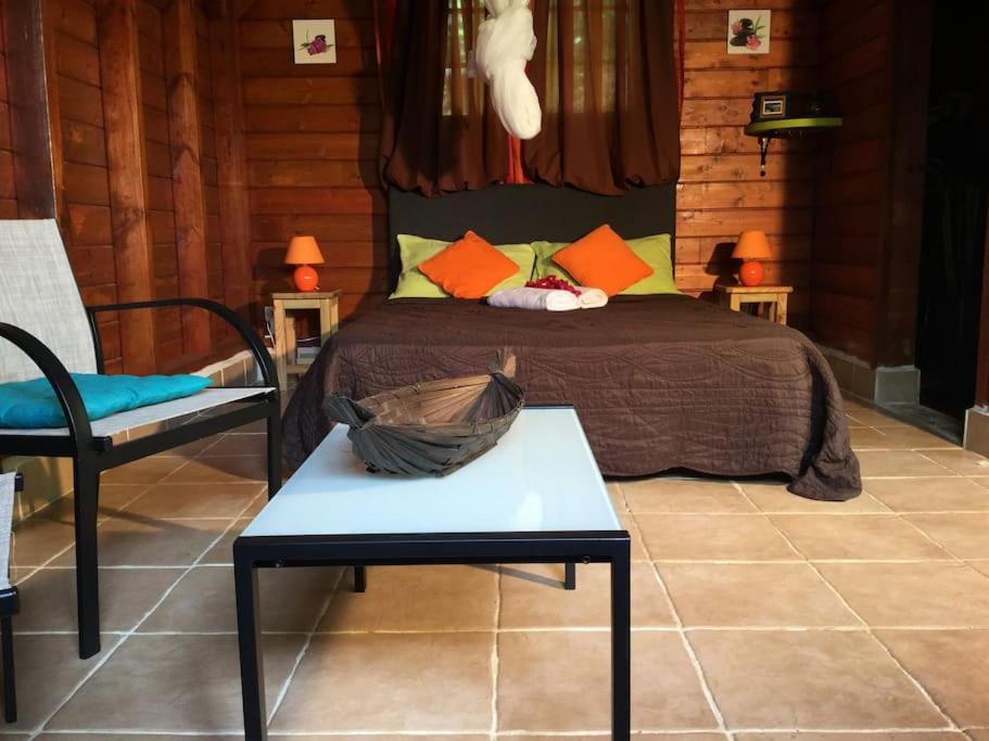 a bedroom with a bed and a table and a chair at 1 bungalow en bois type chalet in Sainte-Anne