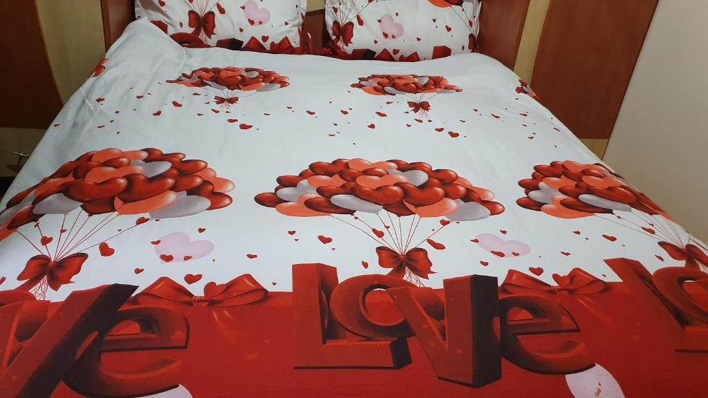 a bed with a sign that says love with flowers on it at Apartamentul Oaspetilor in Slatina