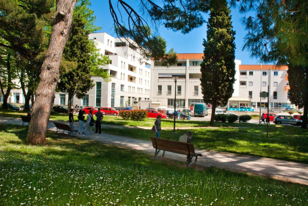 a park with people sitting on a bench in the grass at Apartment Laura in Pula