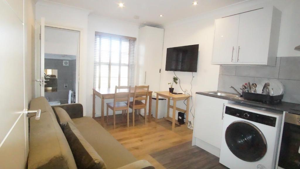 a kitchen and living room with a couch and a table at London Apartments 4U in London