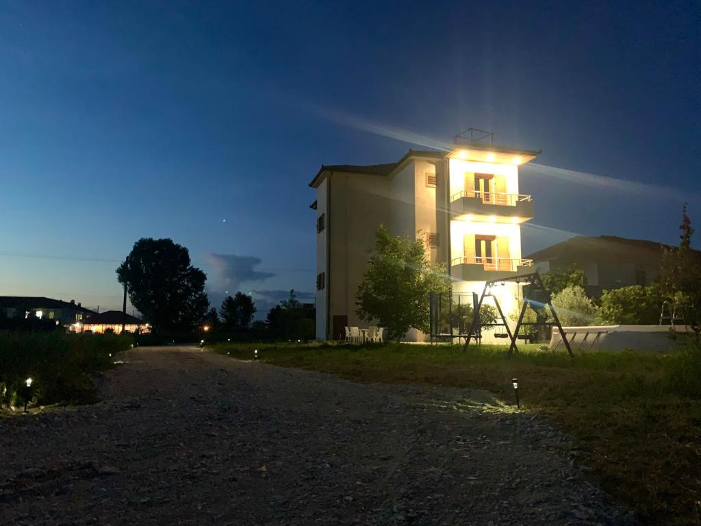 un grand bâtiment avec des lumières allumées la nuit dans l'établissement Villa Apollonia Guest House, à Fier