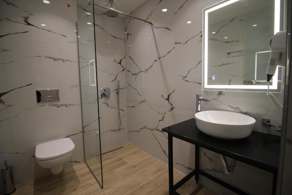 a bathroom with a sink and a toilet and a mirror at Julia Hotel in Sarandë