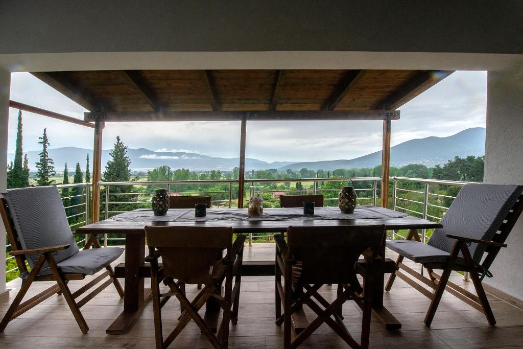uma sala de jantar com uma mesa e cadeiras numa varanda em Lilaia's View em Lílaia