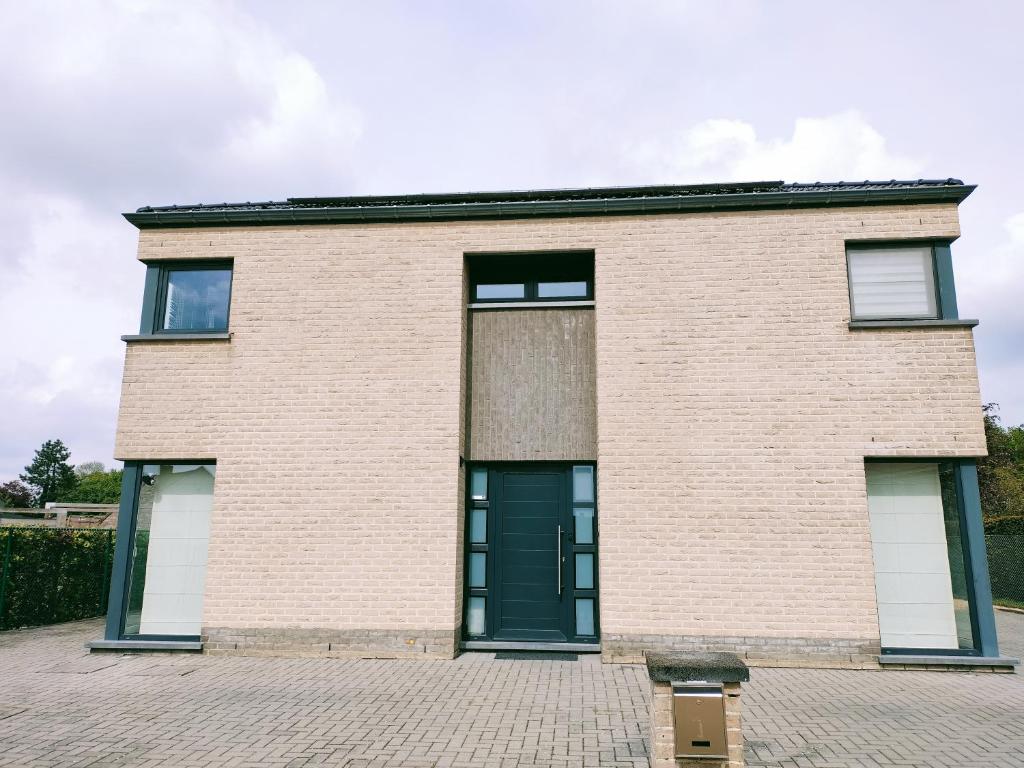 una casa de ladrillo con una puerta verde en In Het Spoor Van De Vos, en Zutendaal