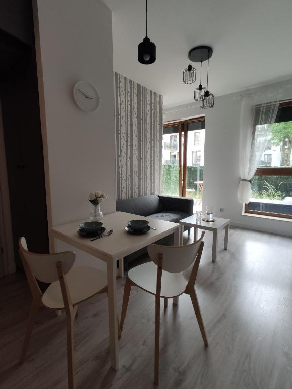 Biały salon ze stołem i krzesłami w obiekcie Nowoczesny apartament dla par w Krakowie
