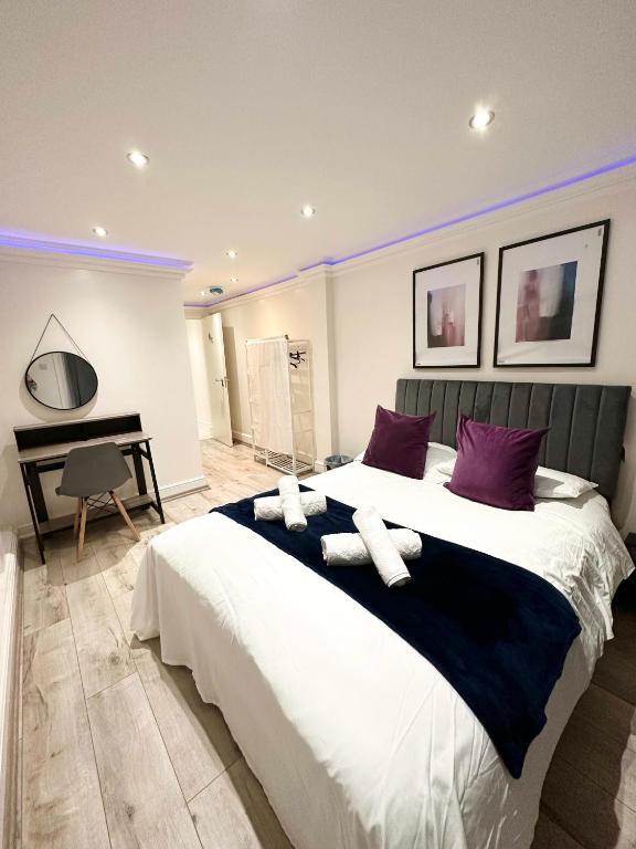 a bedroom with a large bed with purple pillows and a piano at Stylish 3-Bedroom Flat in Prime Location in London