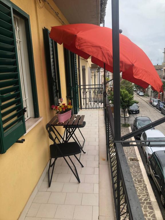 patio con sombrilla roja y sillas en el balcón en Casa Angela, en Vasto