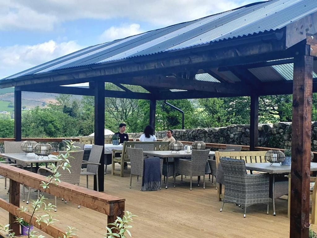 Due persone sedute ai tavoli sotto un padiglione di The Log Cabin @ The Old Forge Glamping a Tullow
