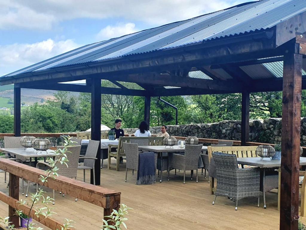 two people sitting at tables under a pavilion at The Log Cabin @ The Old Forge Glamping in Tullow